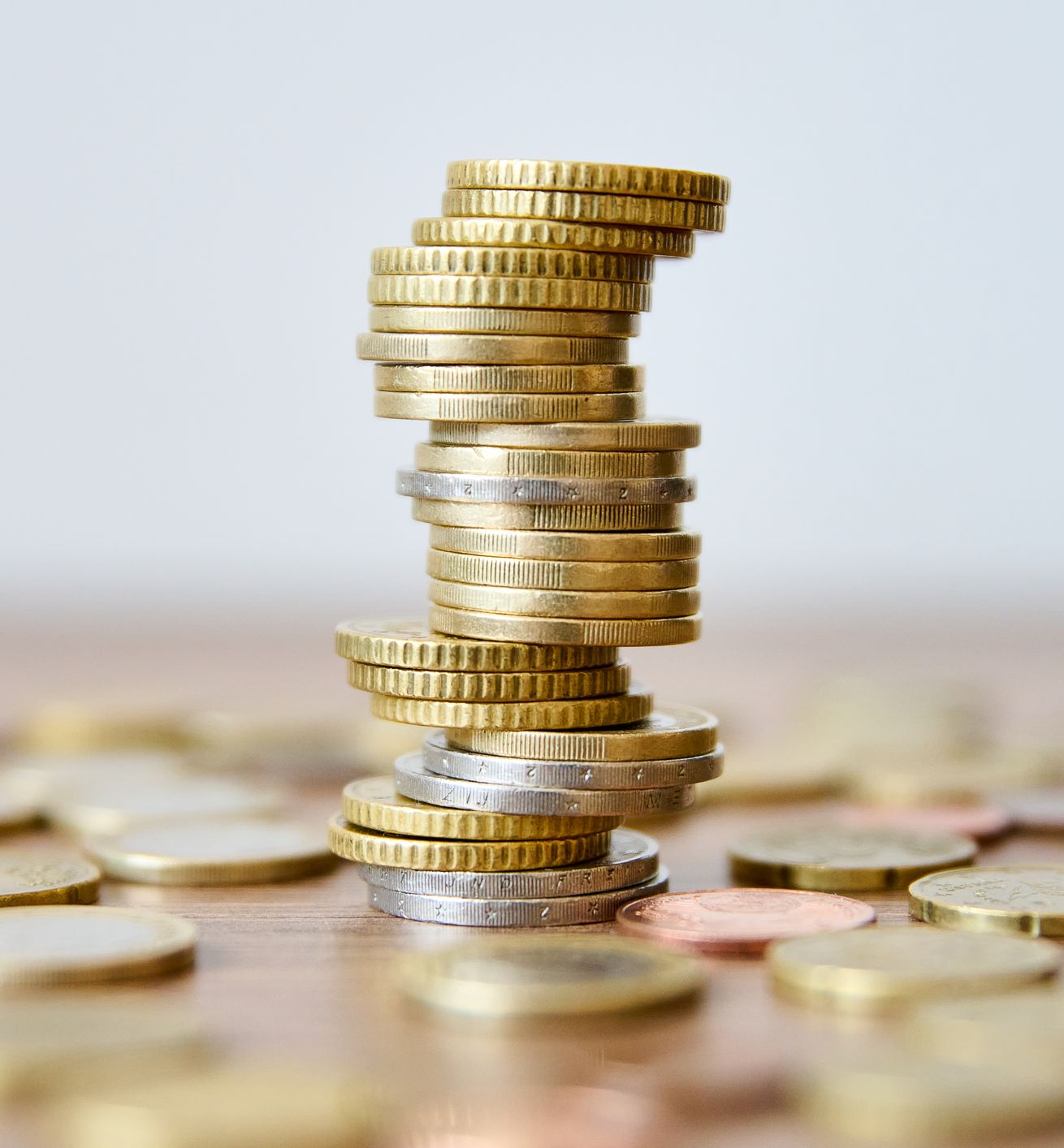 Pile of coins on a wooden table with shallow depth of field